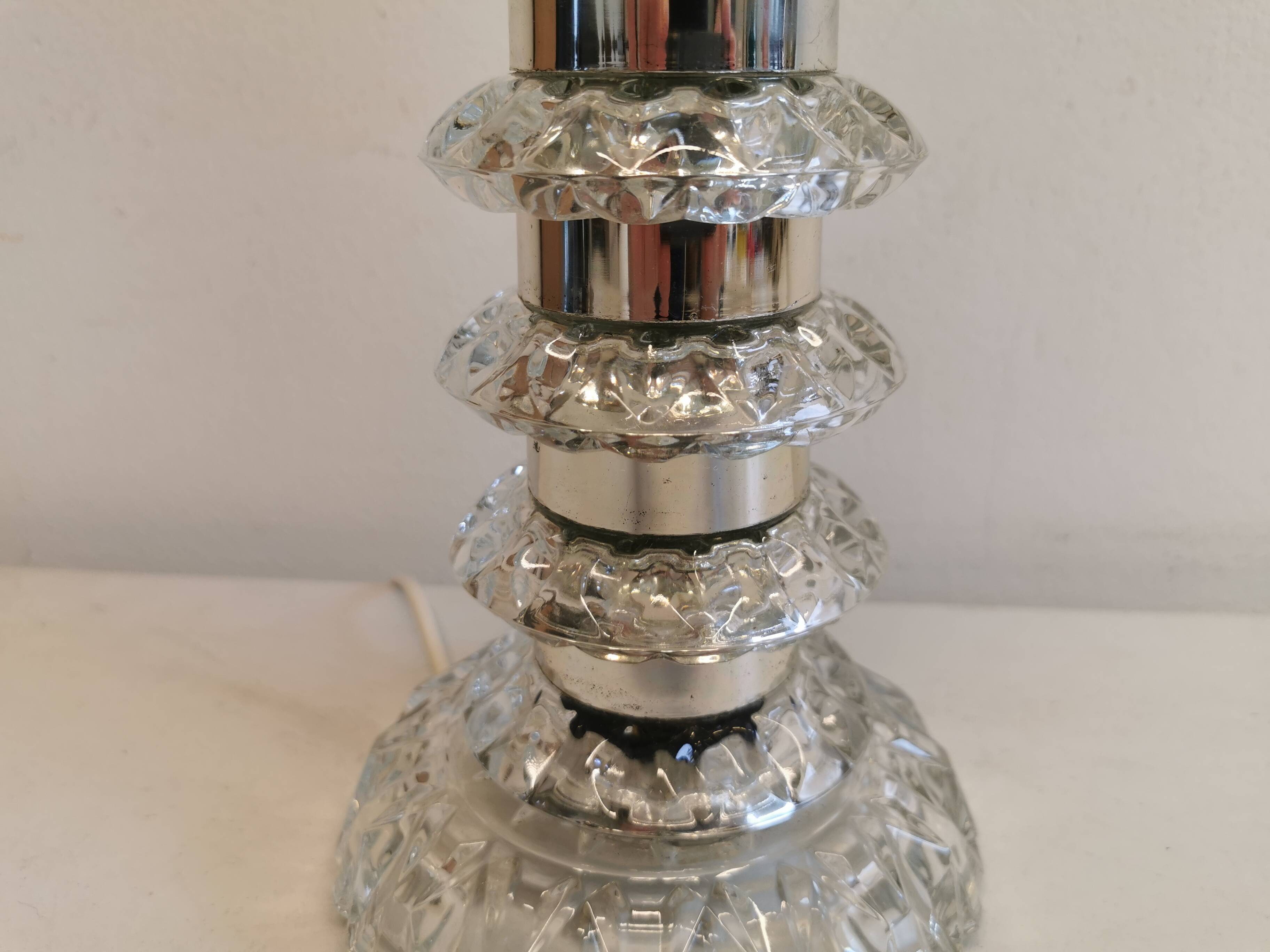 Table lamp made of transparent crystal glass and silver colored spacers.