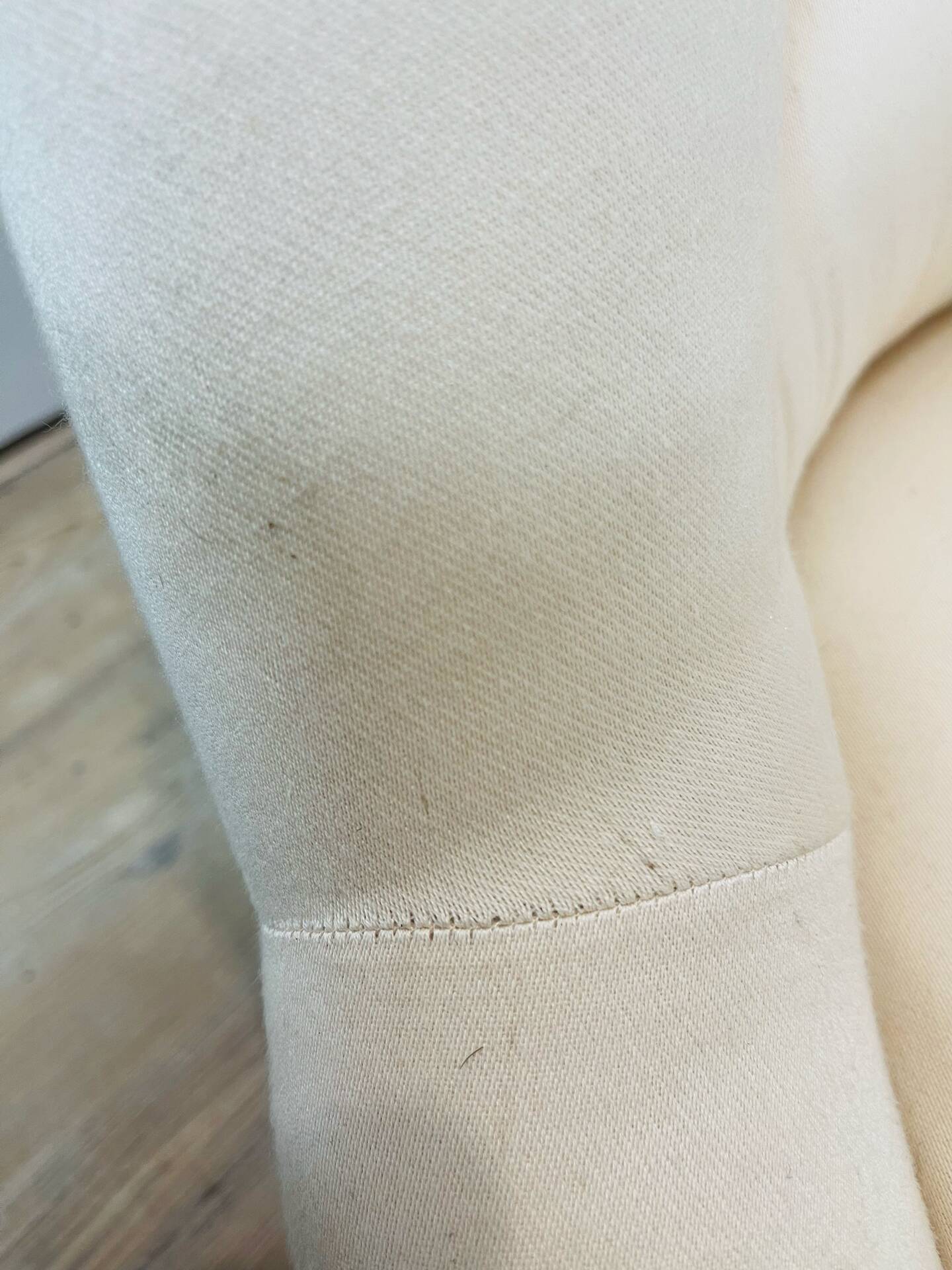 Pale pink upholstered armchair with wooden legs.