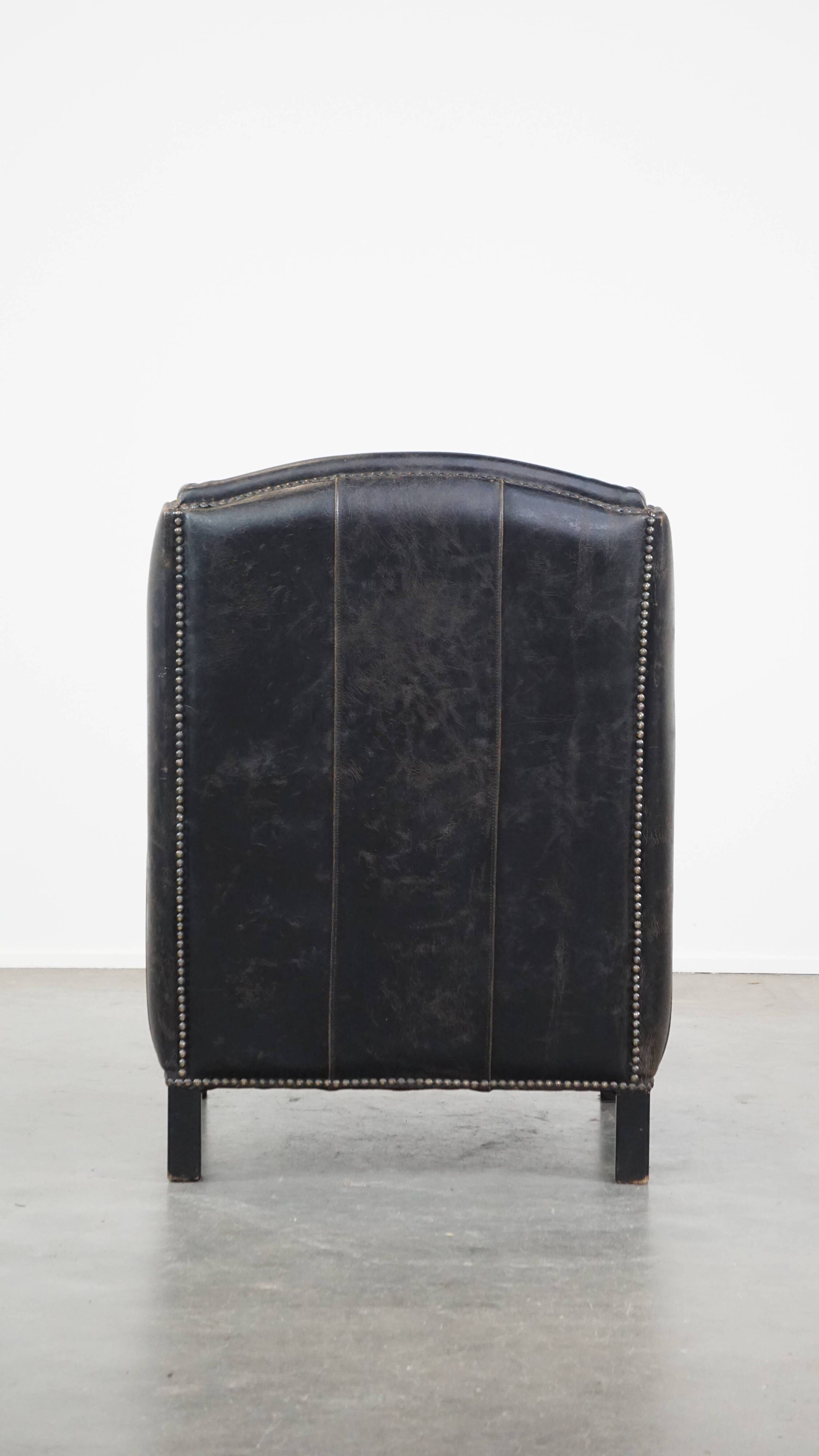 Black cow leather armchair finished with decorative nails, industrial style
