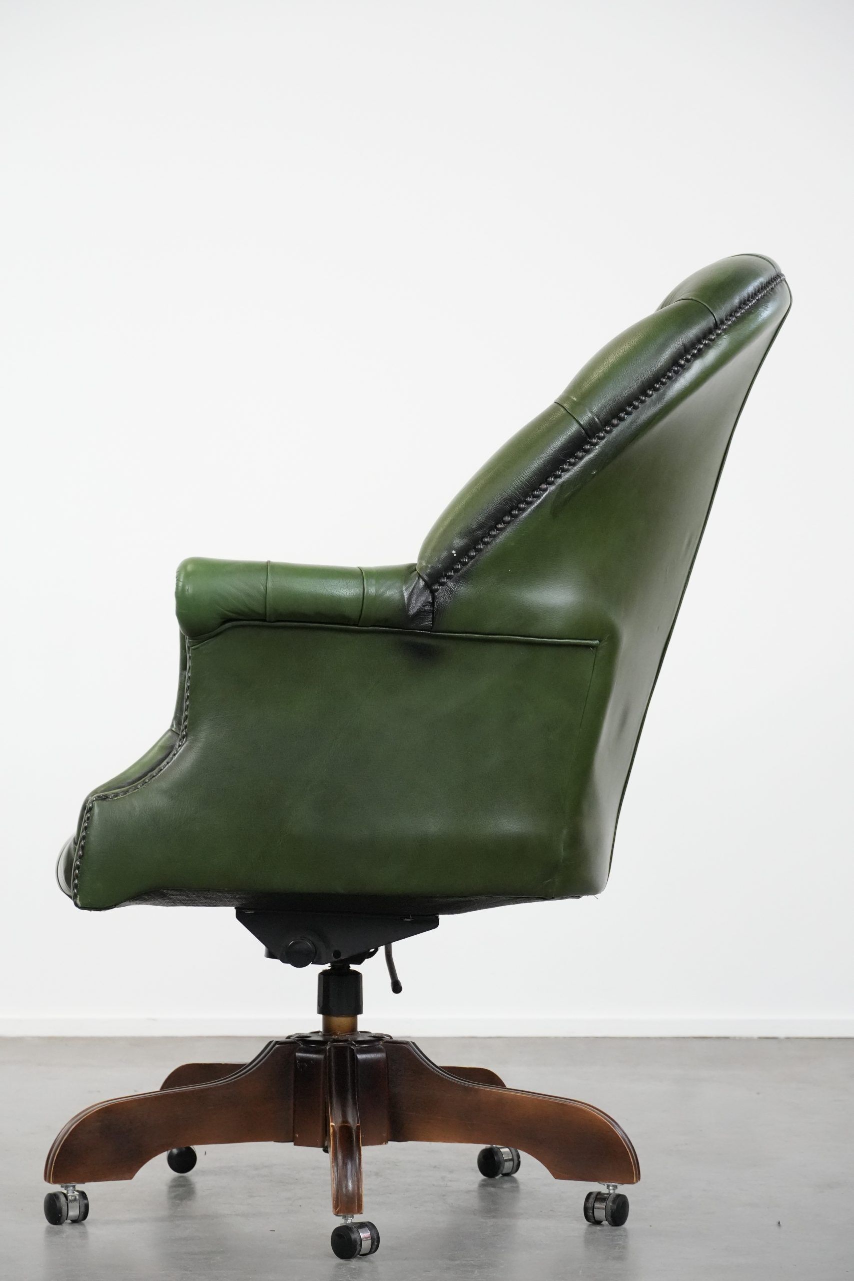 Large green cowhide Chesterfield office chair in English style on wheels