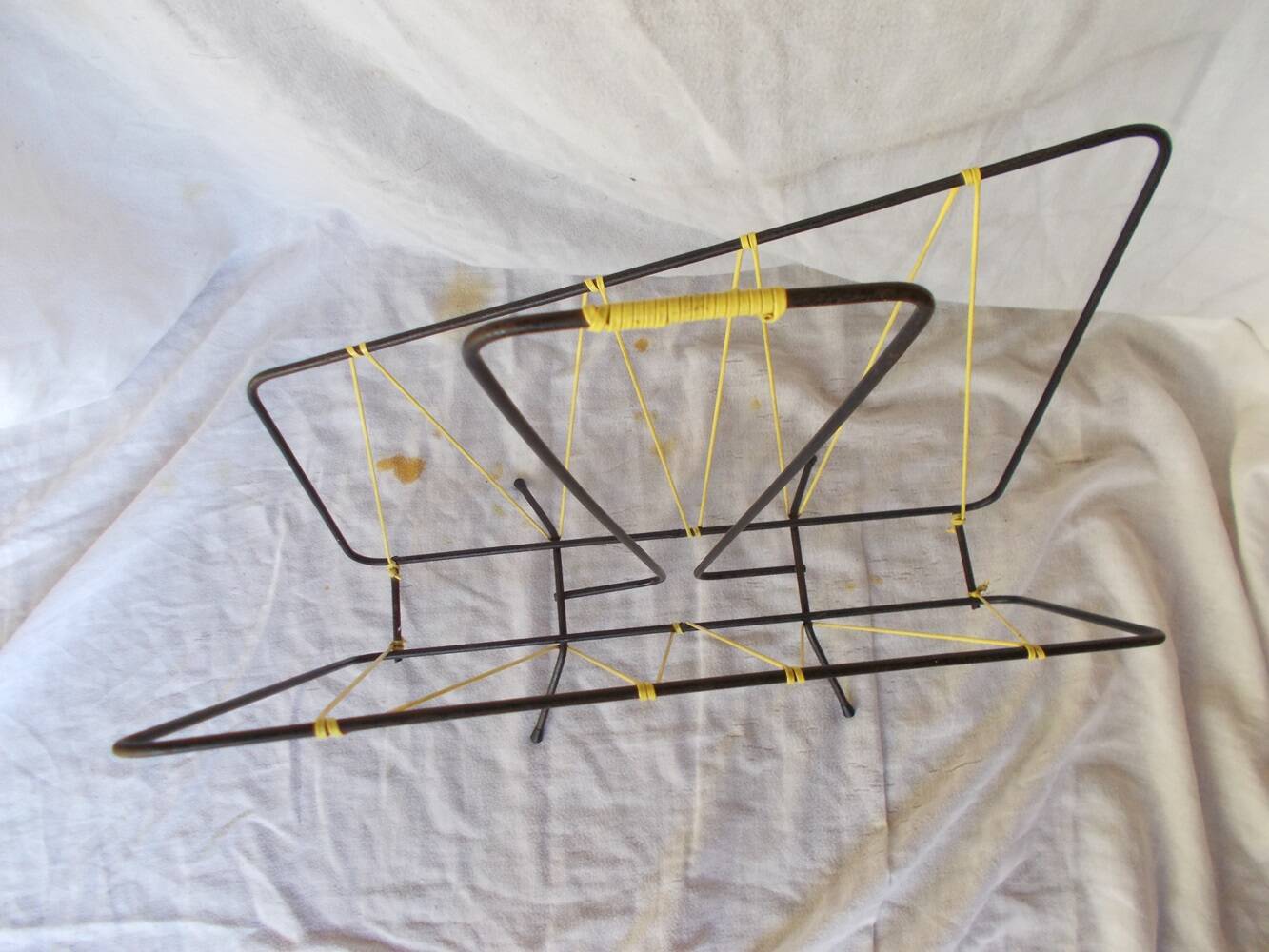 Black metal magazine rack with yellow scoubidou wire.