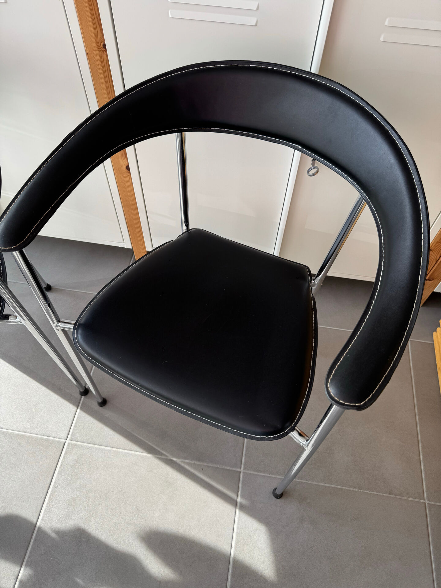 Set of two metal chairs with a brushed finish and black leather.