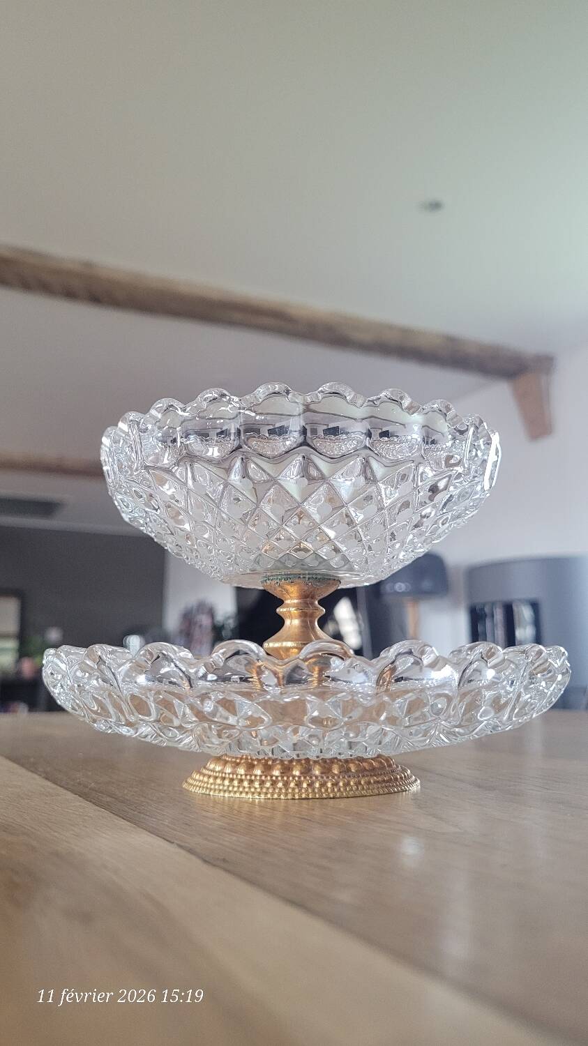 Two-tier display stand in cut glass mounted on a gold metal base.