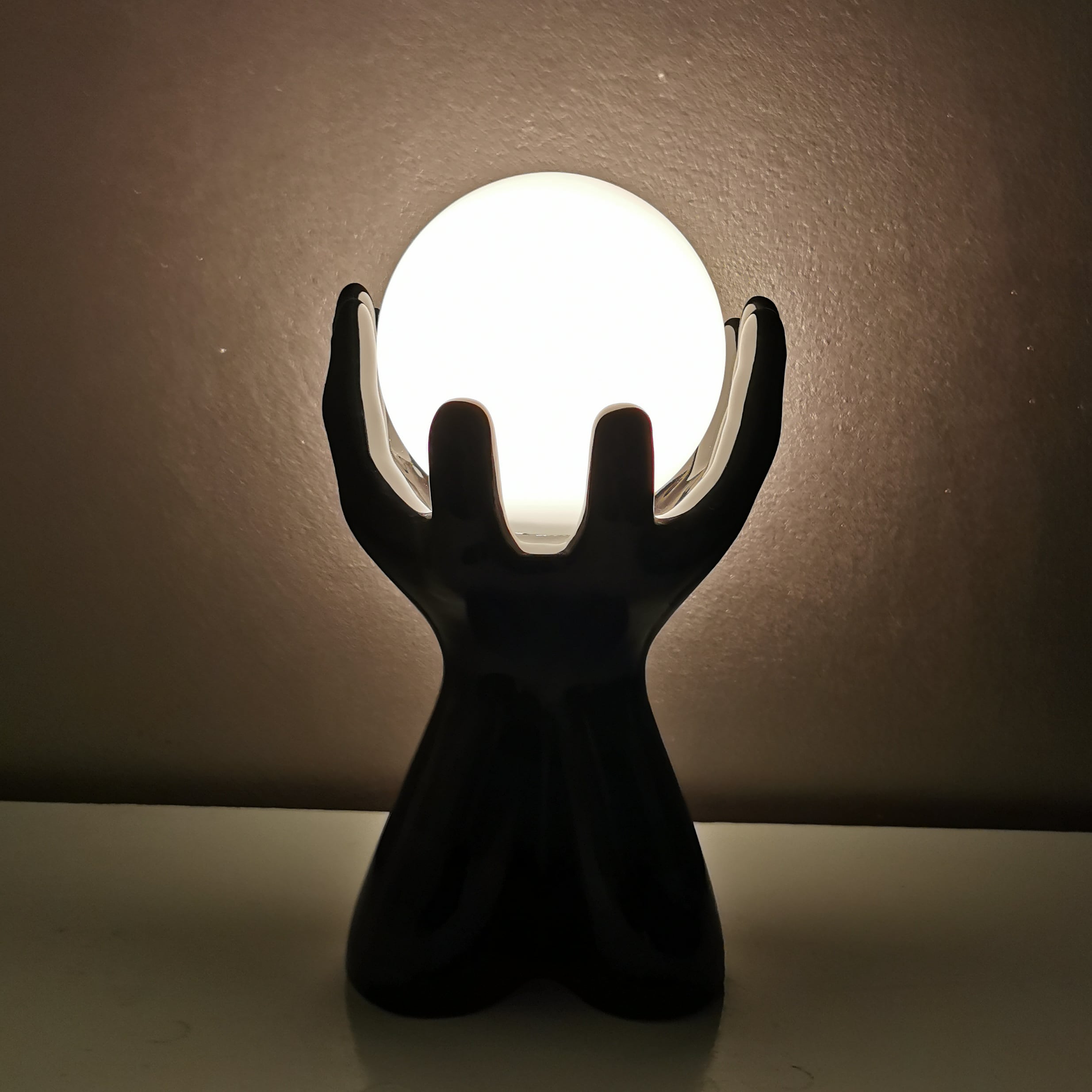 Italian design ceramic table lamp, two hands and glass shade.