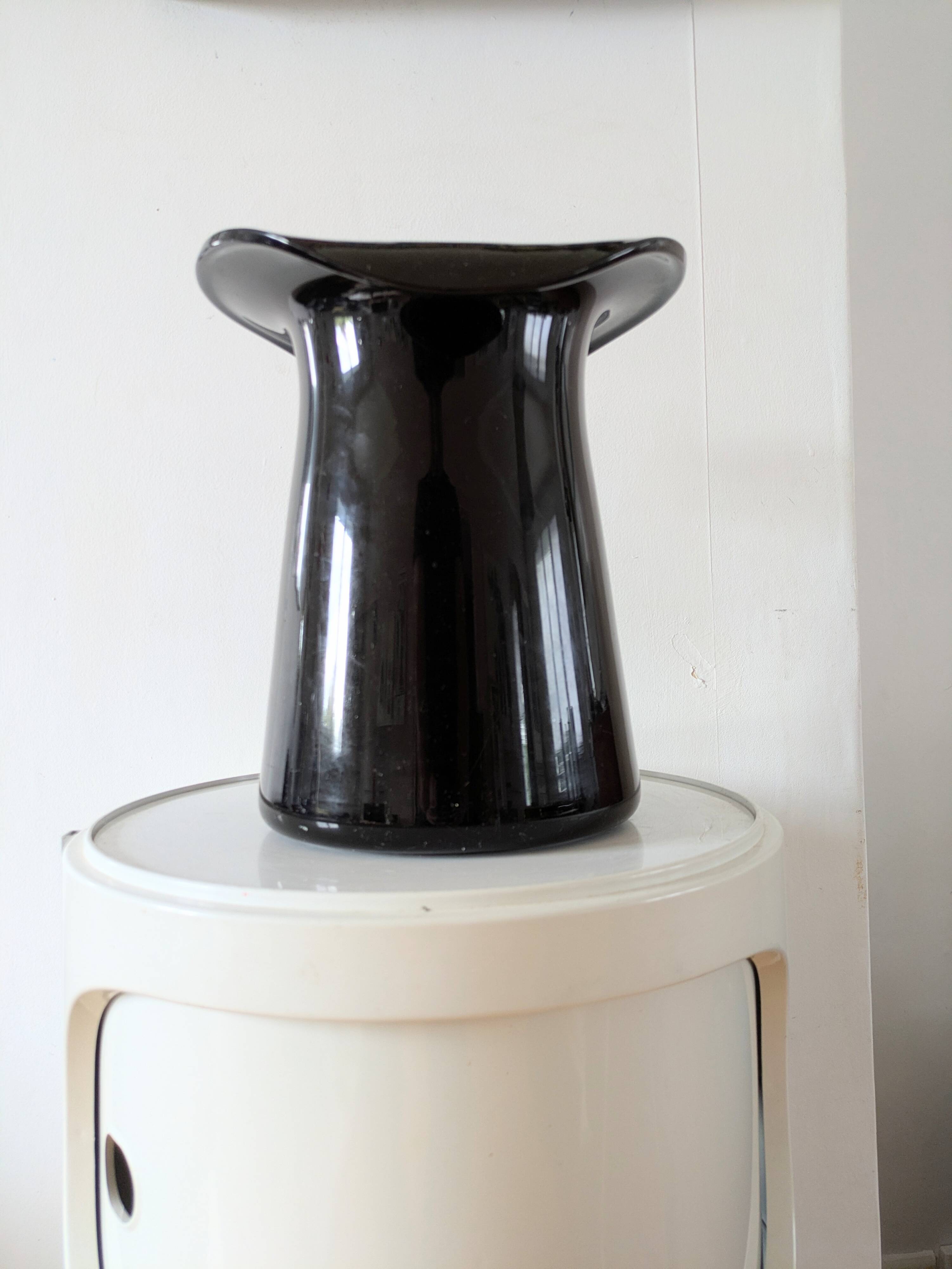 Large black glass vase topped with a 70s hat