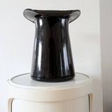 Large black glass vase topped with a 70s hat