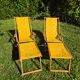 2 vintage Chilean deck chairs made of wood and yellow fabric printed with sailboats, with footrests.