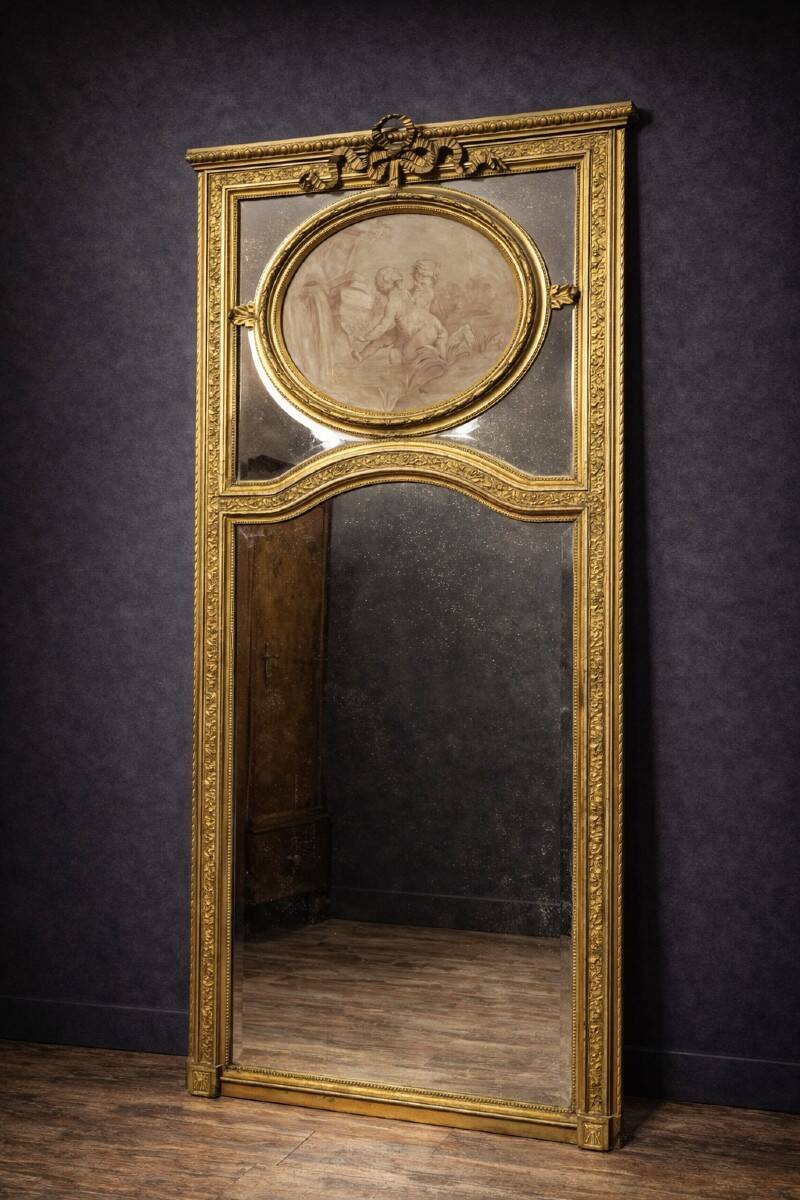 Very large mirror with mouldings, richly carved and gilded, in the Louis XVI style.