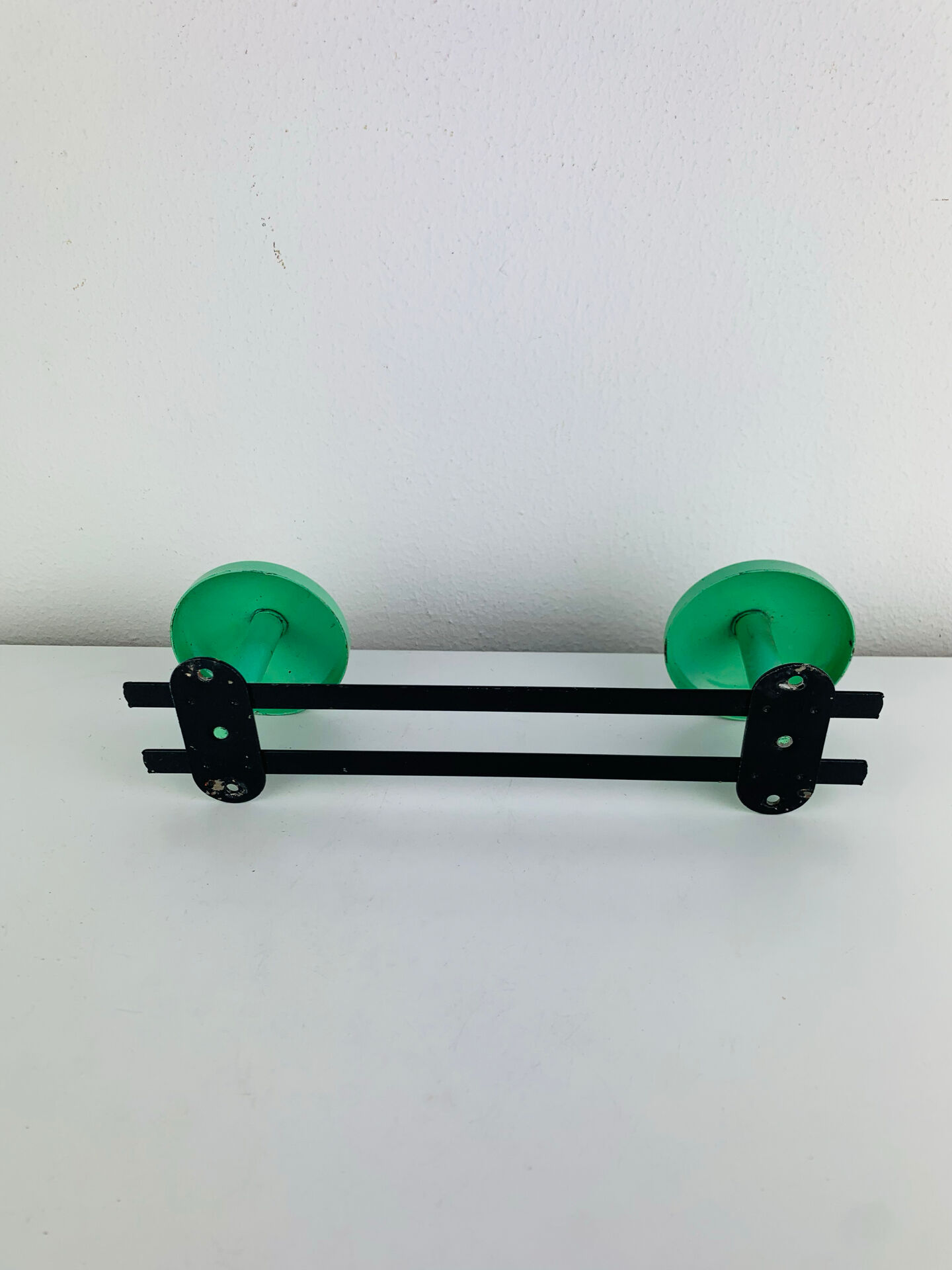 Wall-mounted coat rack with 2 green hooks from the 1950s.