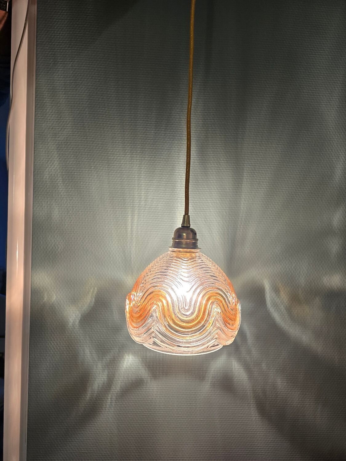 Suspension with amber moulded glass globe featuring wavy patterns.