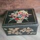 Old black metal box and flowers at the beginning of the century