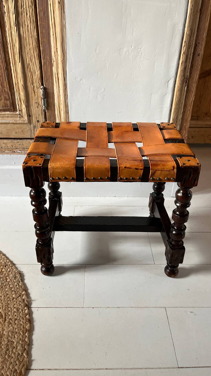 Antique turned wooden stool with woven leather.
