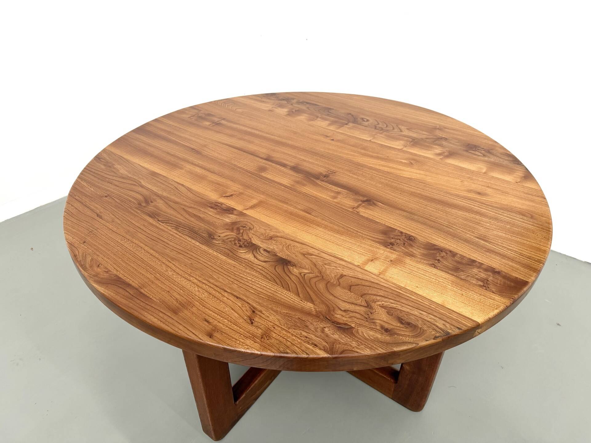 Modernist round table in solid elm, crossed legs.