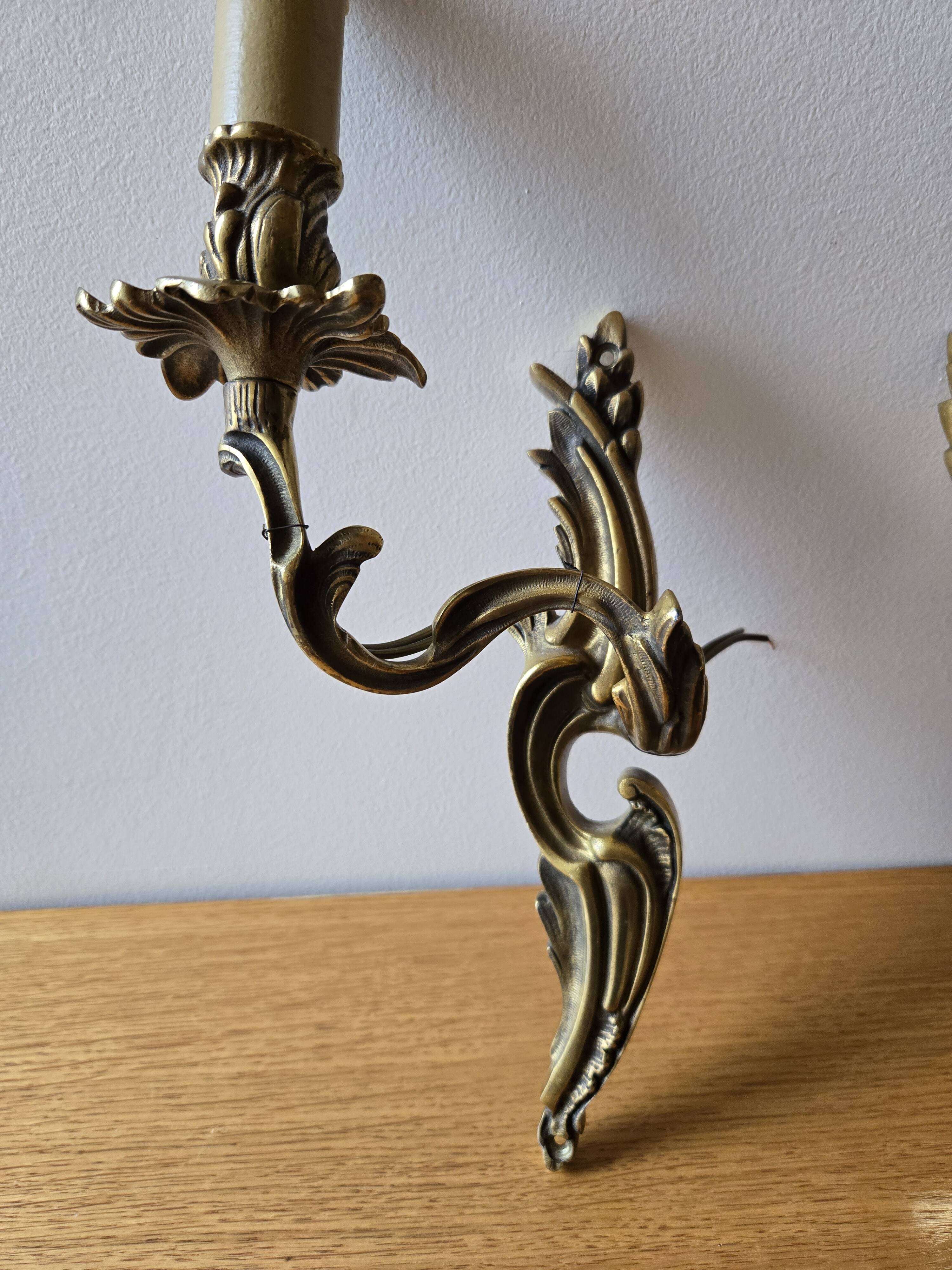 Pair of symmetrical gold wall sconces in baroque style made of bronze.