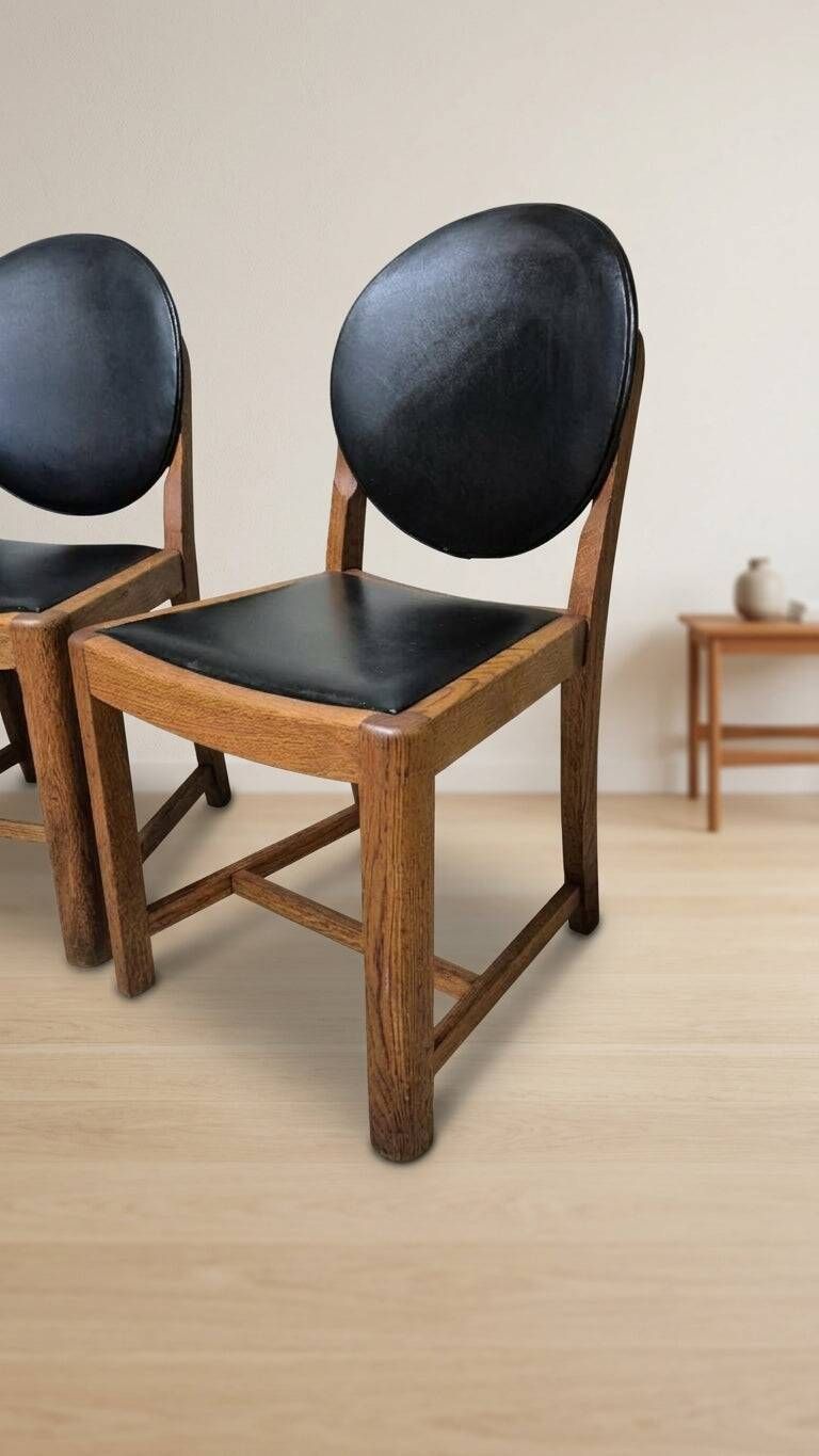 Set of four vintage wooden dining chairs with black leather upholstery
