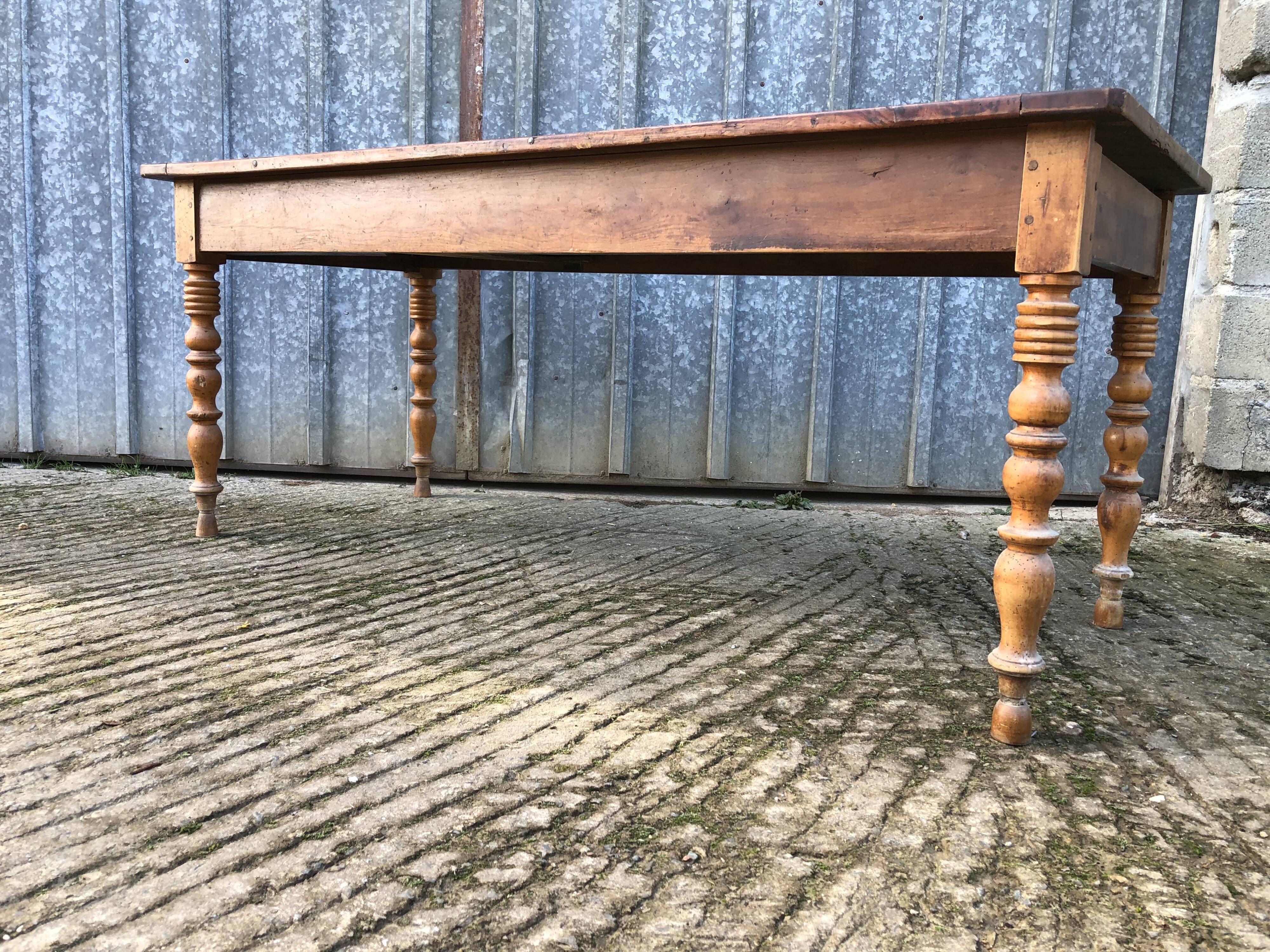 Antique farmhouse table in solid cherry wood with turned legs.