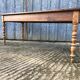 Antique farmhouse table in solid cherry wood with turned legs.
