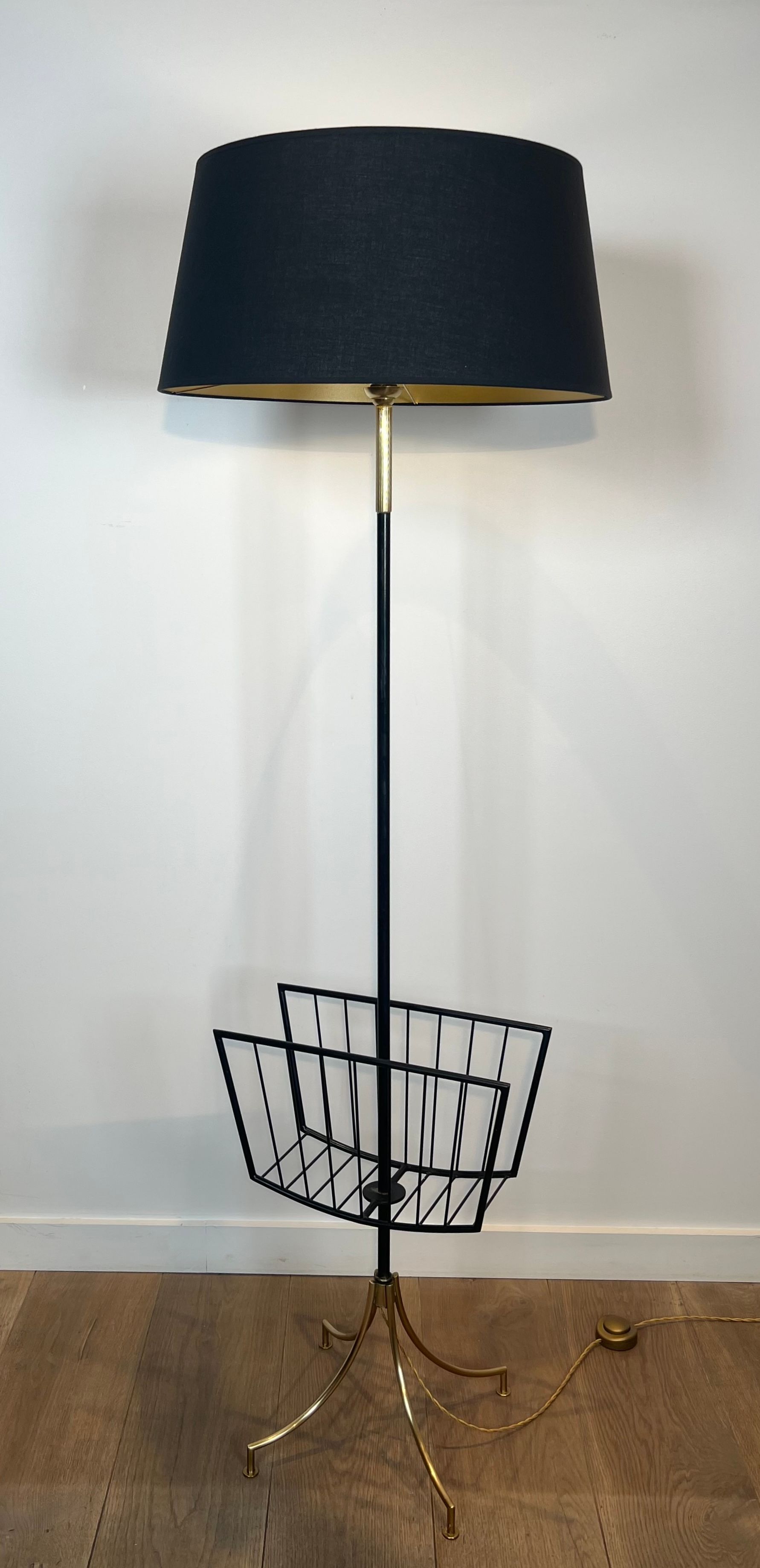 Designer floor lamp in black lacquered metal and brass, incorporating a magazine rack