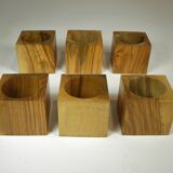 Six egg cups on a wooden tray.