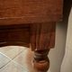 Antique carved wooden bench with green upholstered seat and backrest.