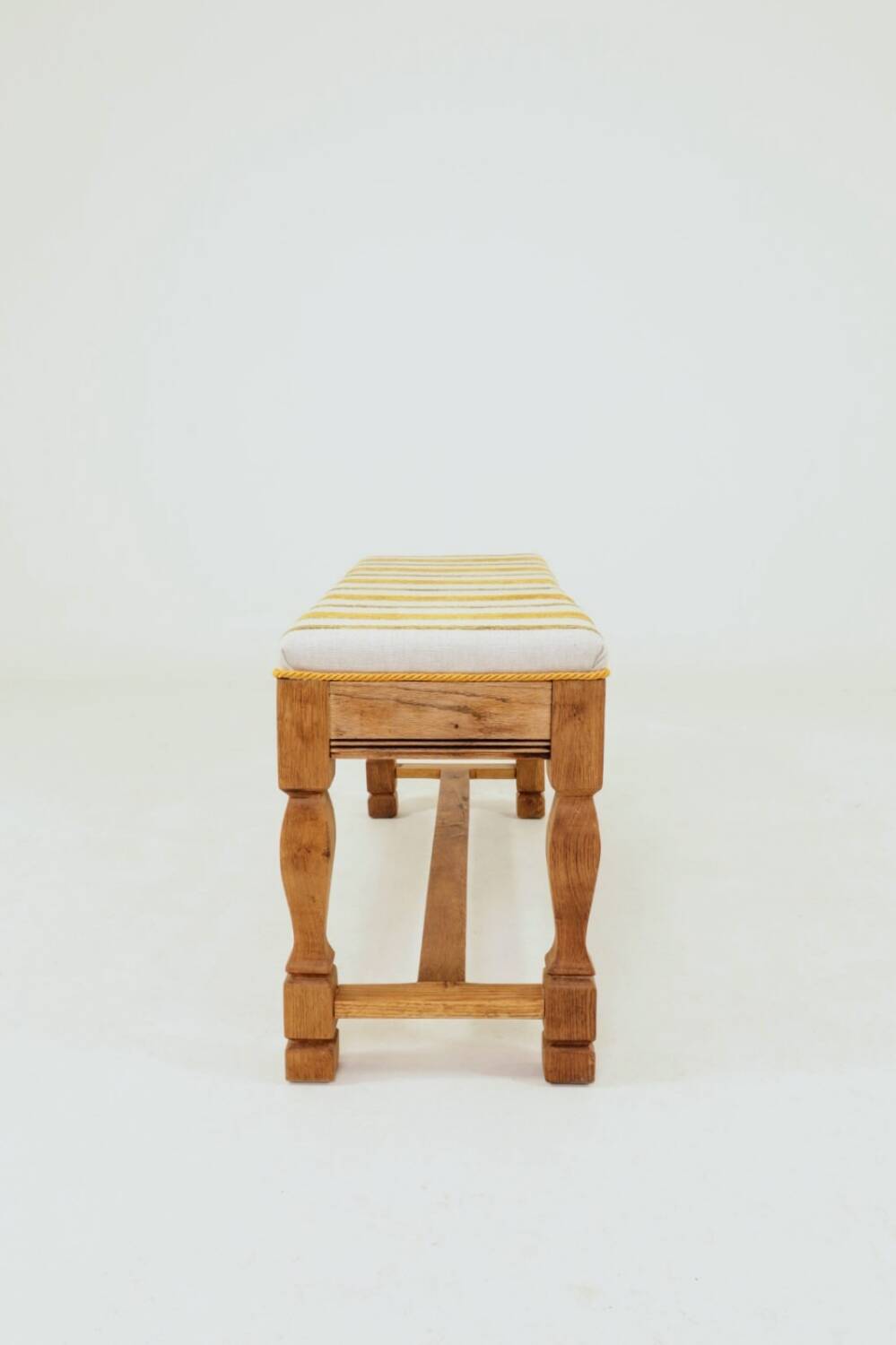 Vintage oak bench with striped linen fabric in a country style.