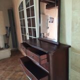 Style set: bevelled mirror and curved wooden chest of drawers.