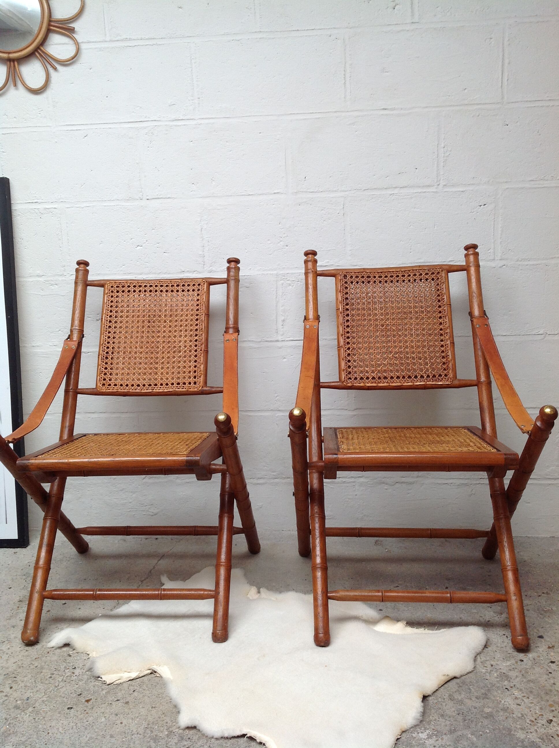 Pair of folding chairs in bamboo and caning, leather and brass