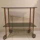 Vintage rolling dessert trolley with smoked glass trays and a golden base.