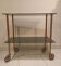 Vintage rolling dessert trolley with smoked glass trays and a golden base.
