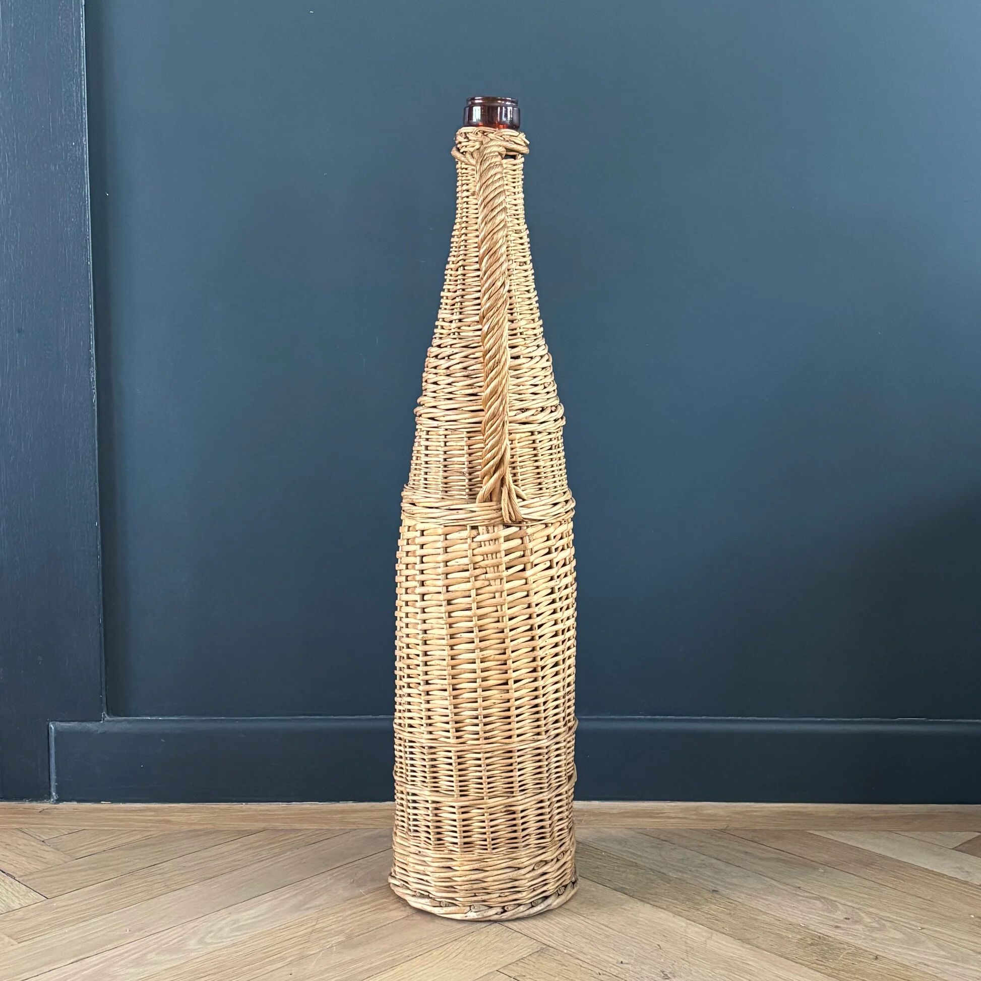 Amber glass bottle in its wicker handle basket.