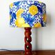 Turned wooden lamp with a lampshade featuring lemon tiles.