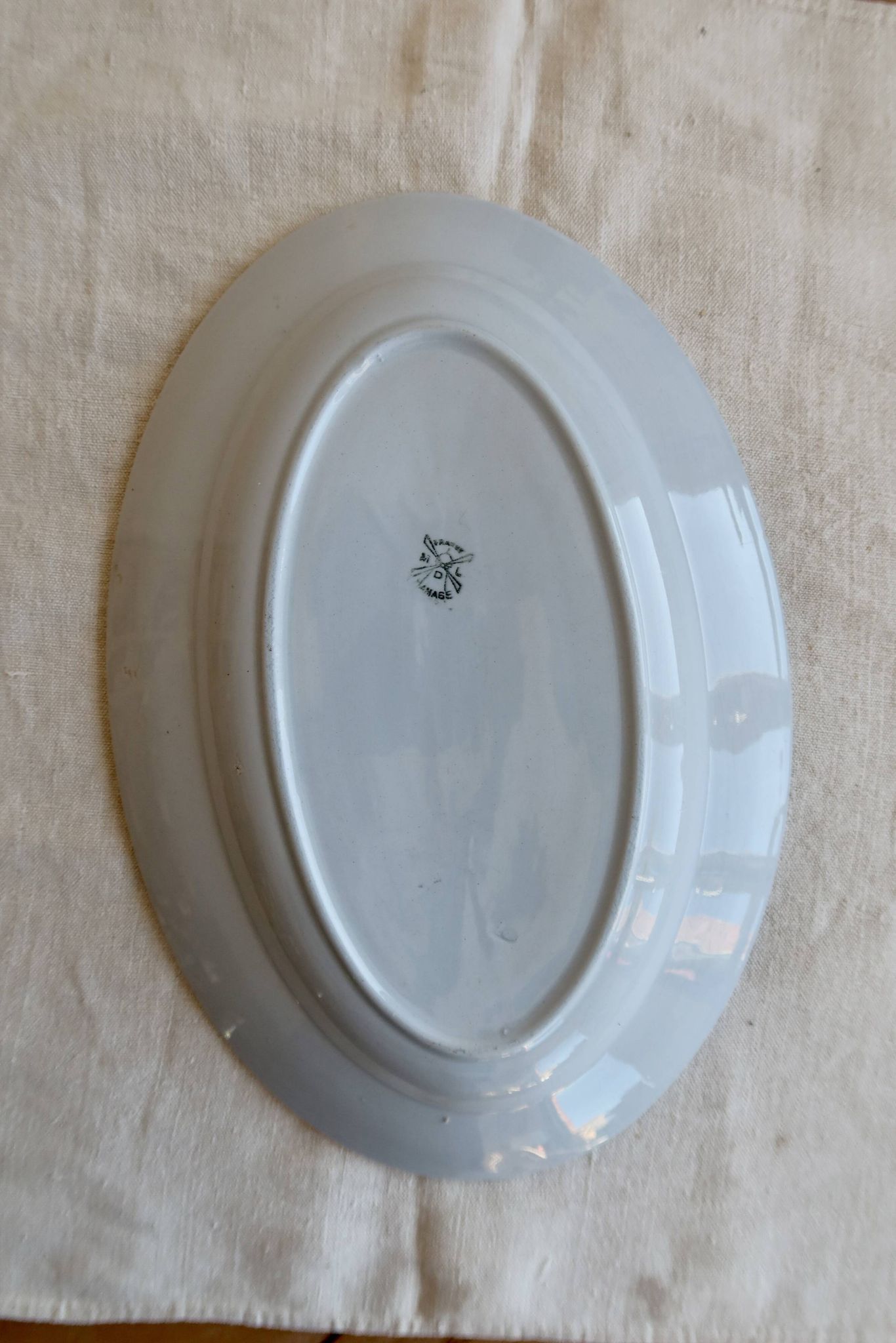 Antique oval serving dish in pale blue earthenware with a small flower design.