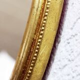 Golden oval mirror with leaf