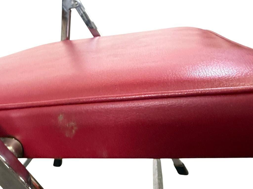 Vintage folding chair in red faux leather with a chrome frame.