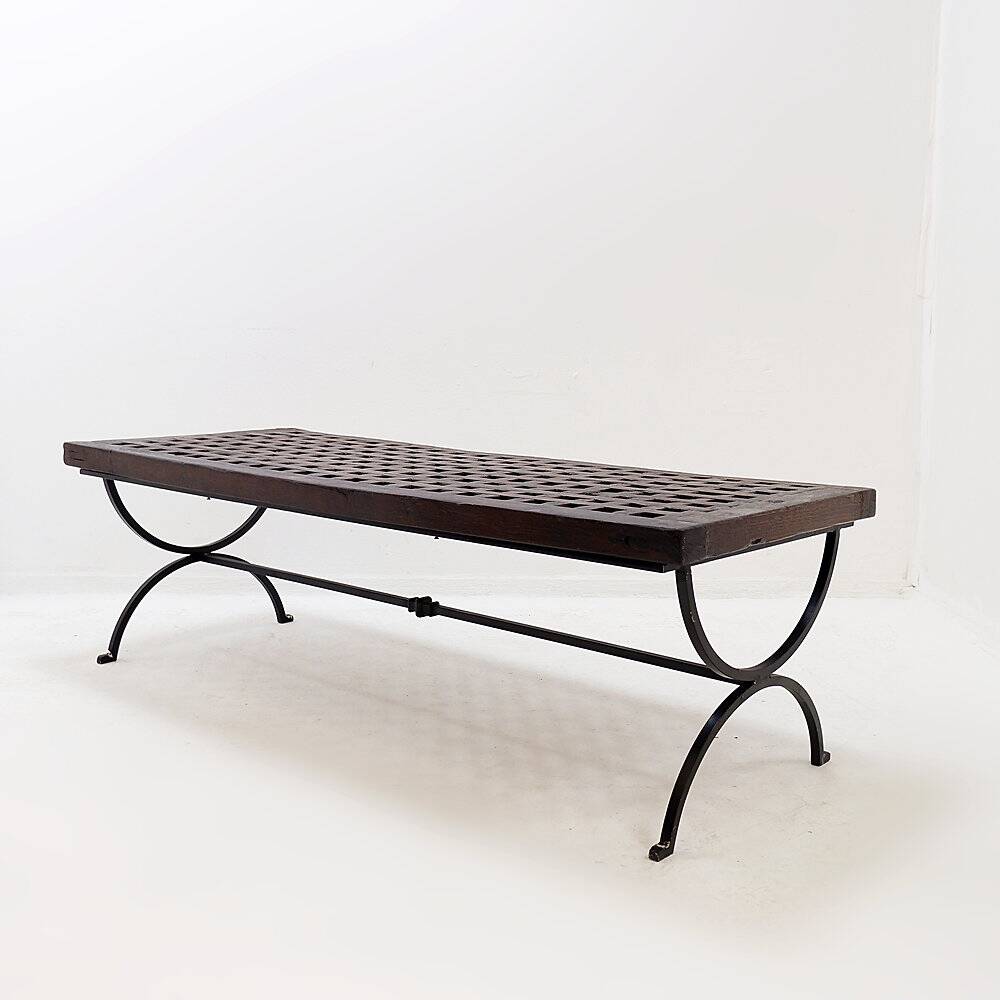 Solid wood coffee table with an openwork design and wrought iron legs.