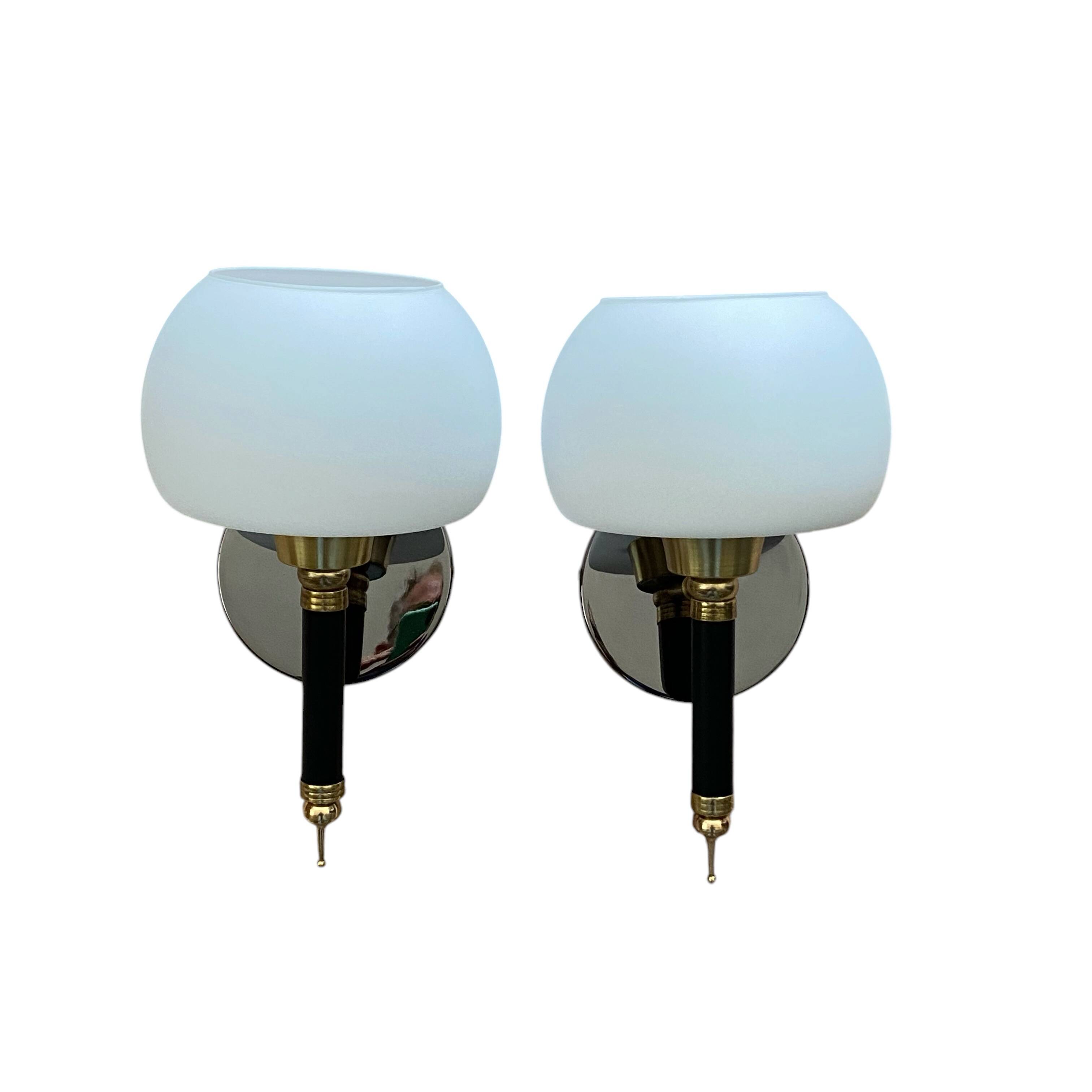 Pair of wall sconces with brass torch and white glass globe.