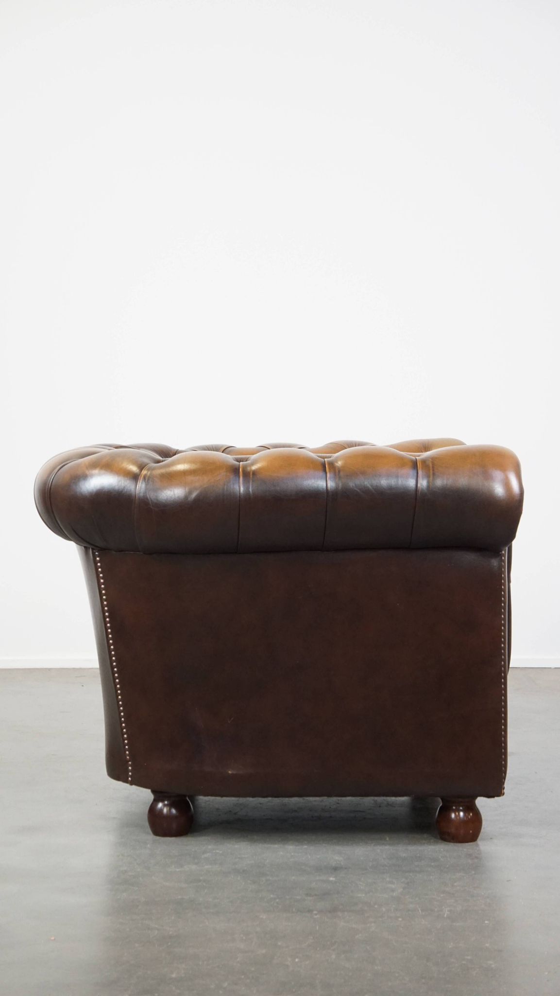 A well-maintained cowhide leather English Chesterfield armchair