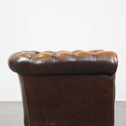 A well-maintained cowhide leather English Chesterfield armchair