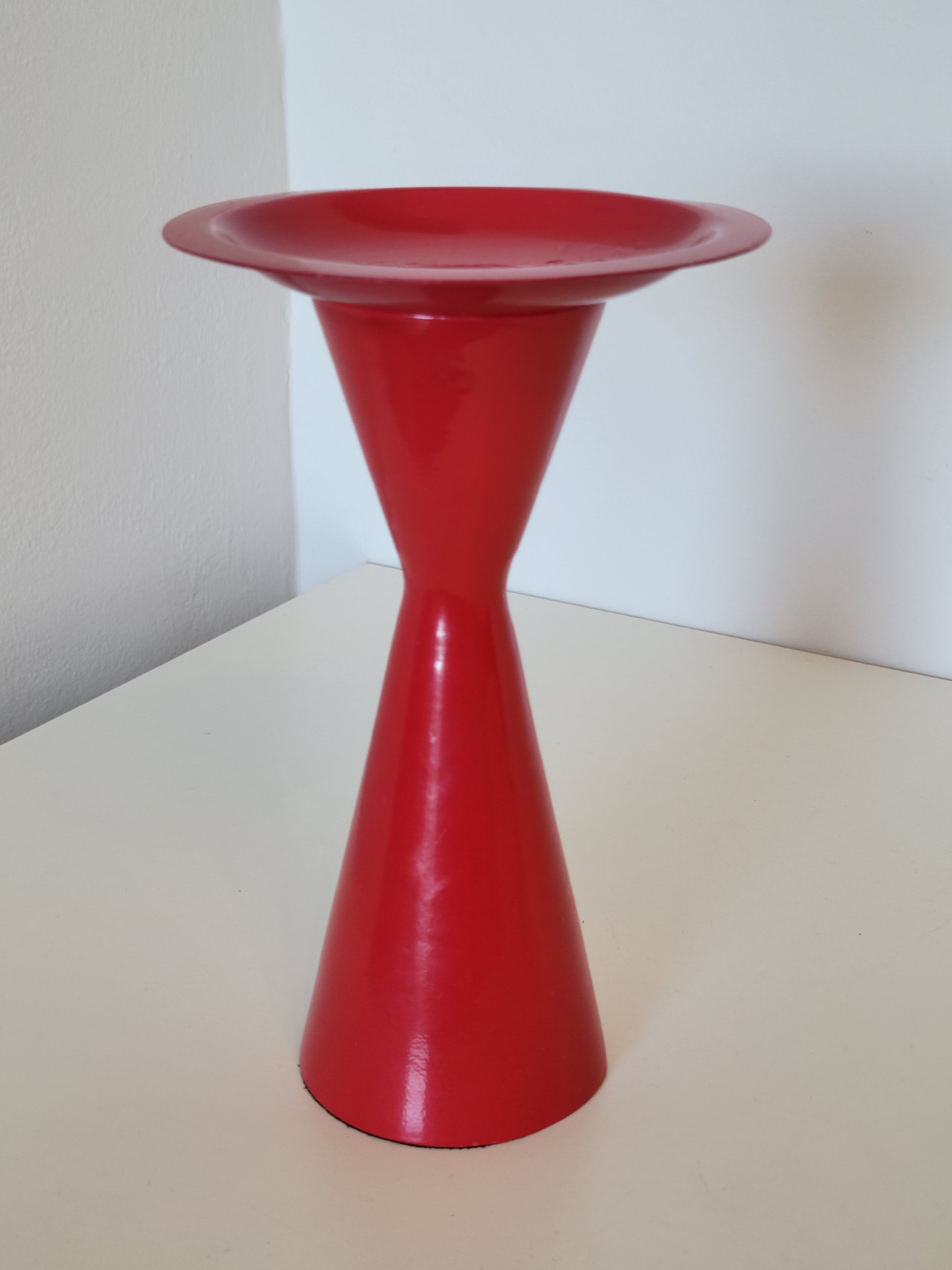 Vintage design candlestick in red metal in the shape of an hourglass