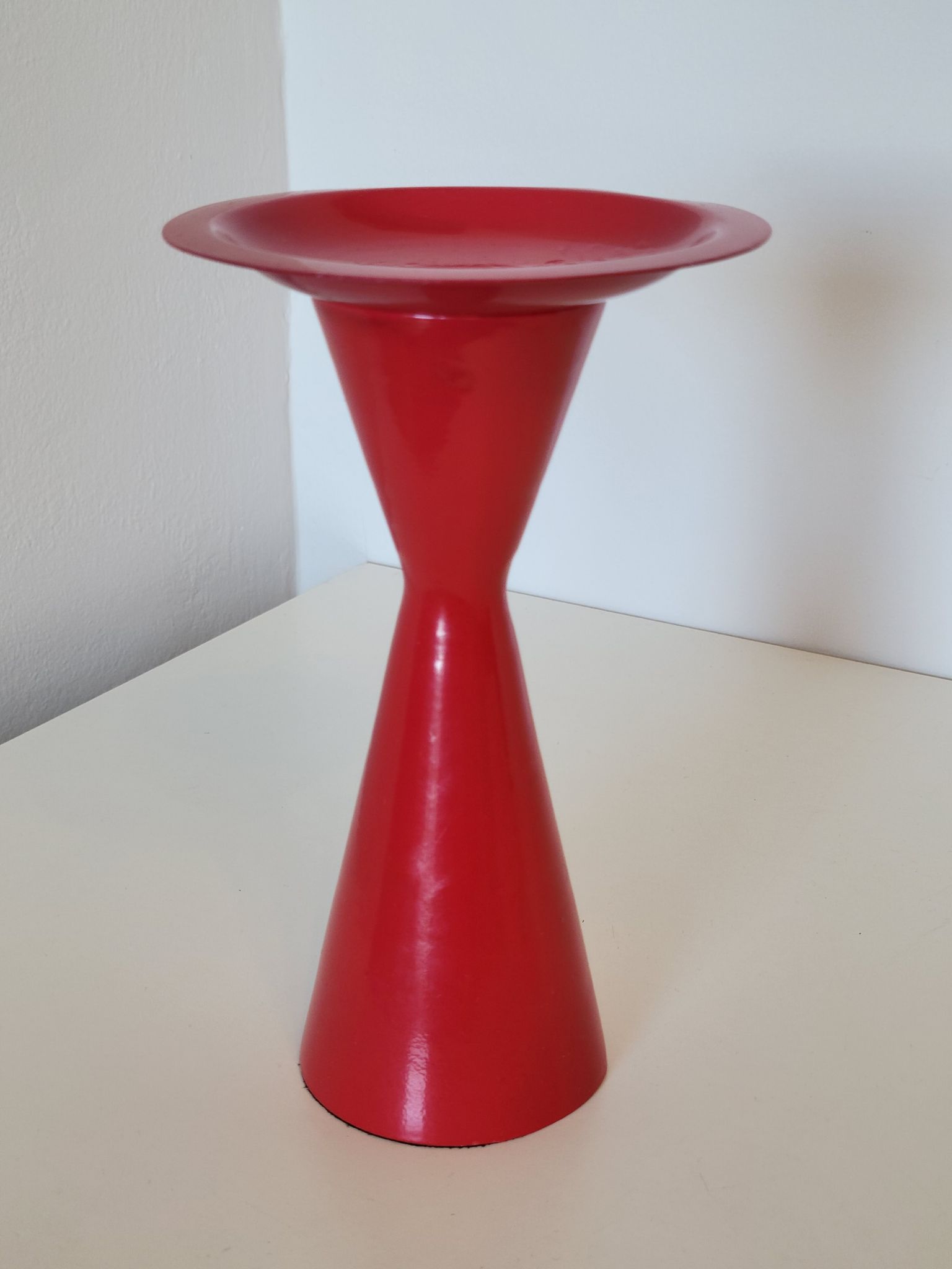 Vintage design candlestick in red metal in the shape of an hourglass