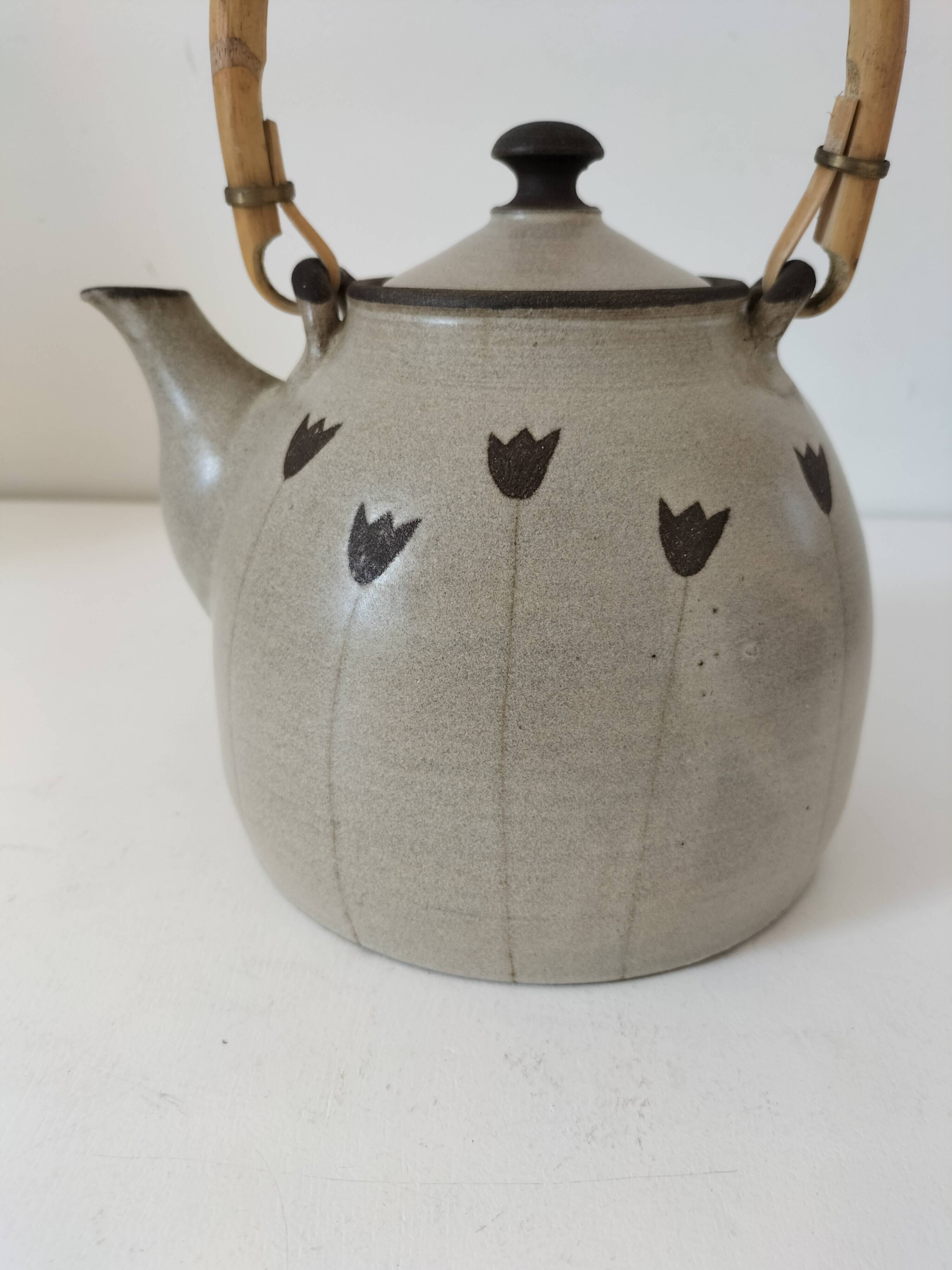 Beige stoneware teapot with stylized flowers and rattan handle