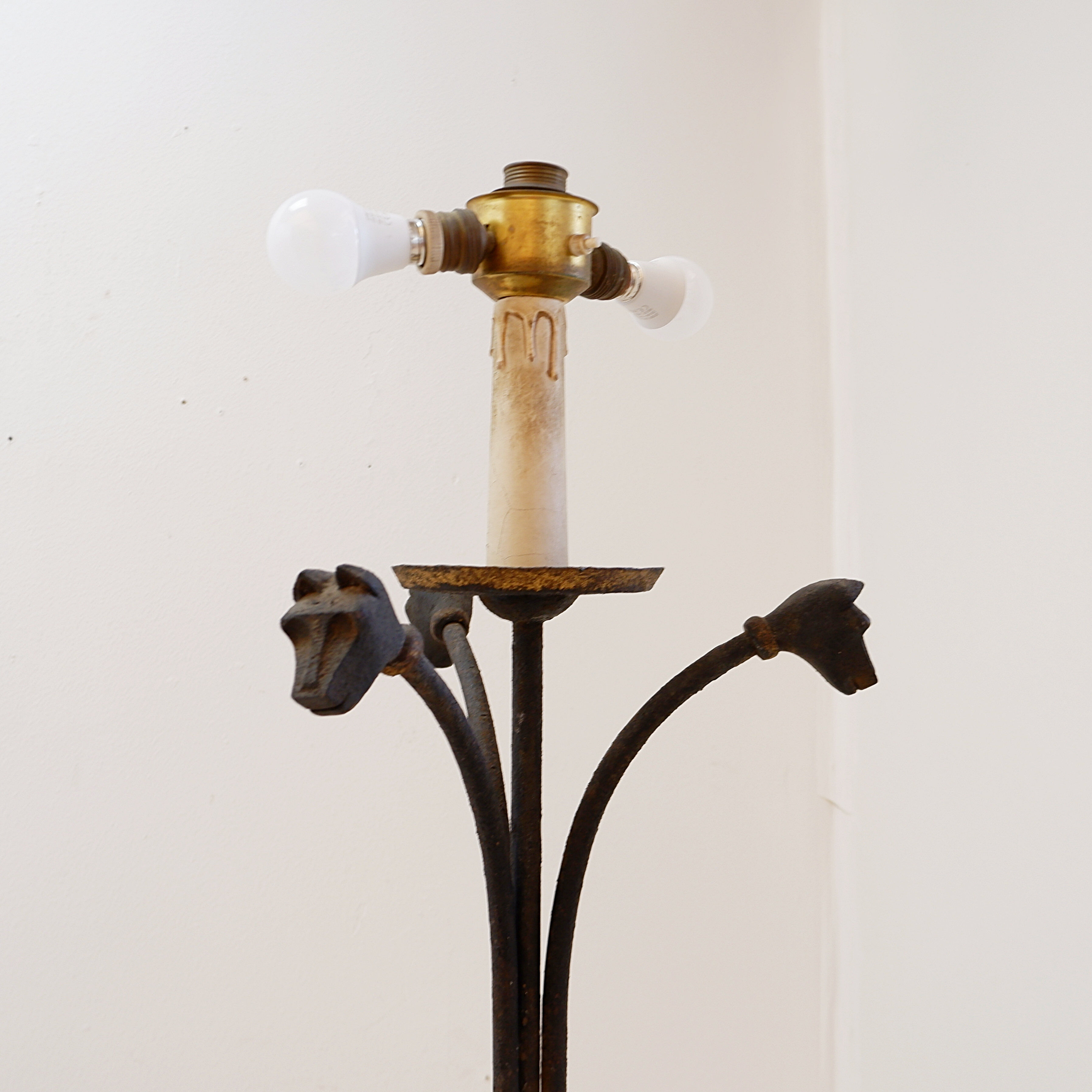 Wrought iron tripod floor lamp decorated with stylized animal heads