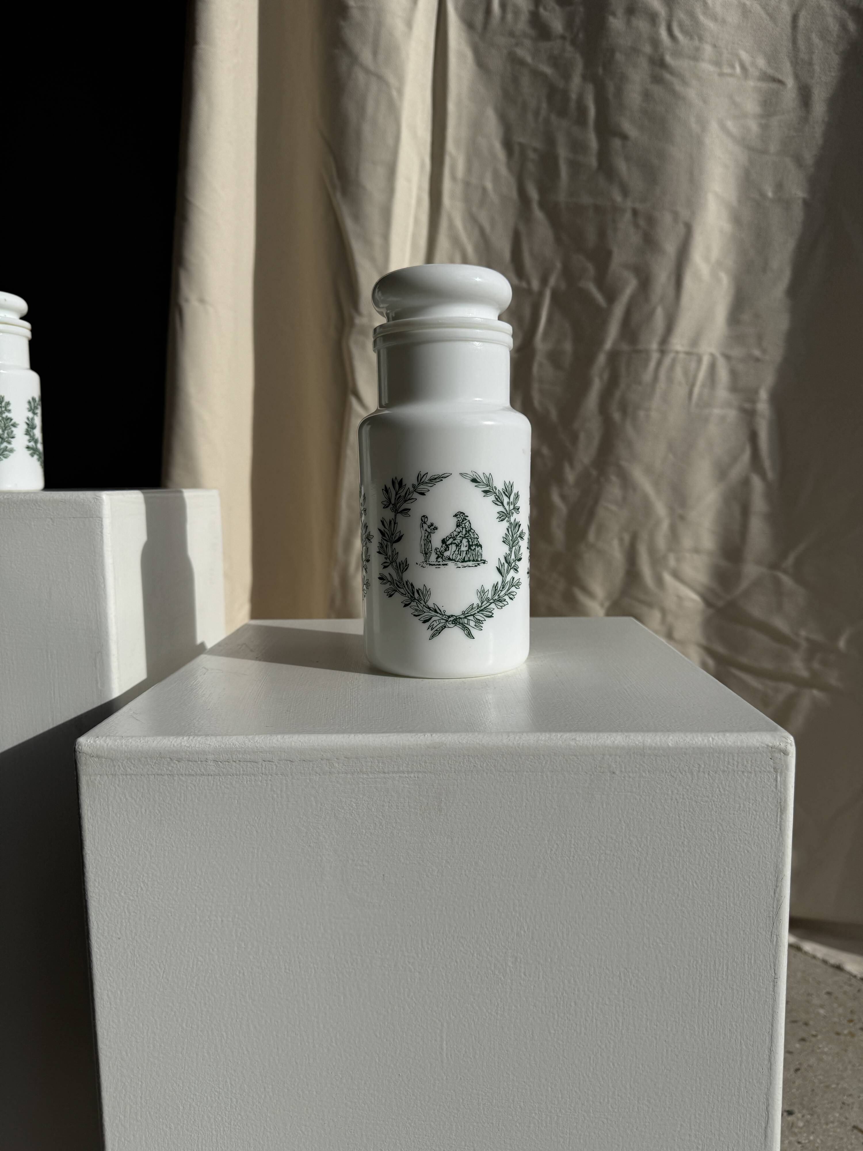 A pair of white glass bottles with Italian green patterns.