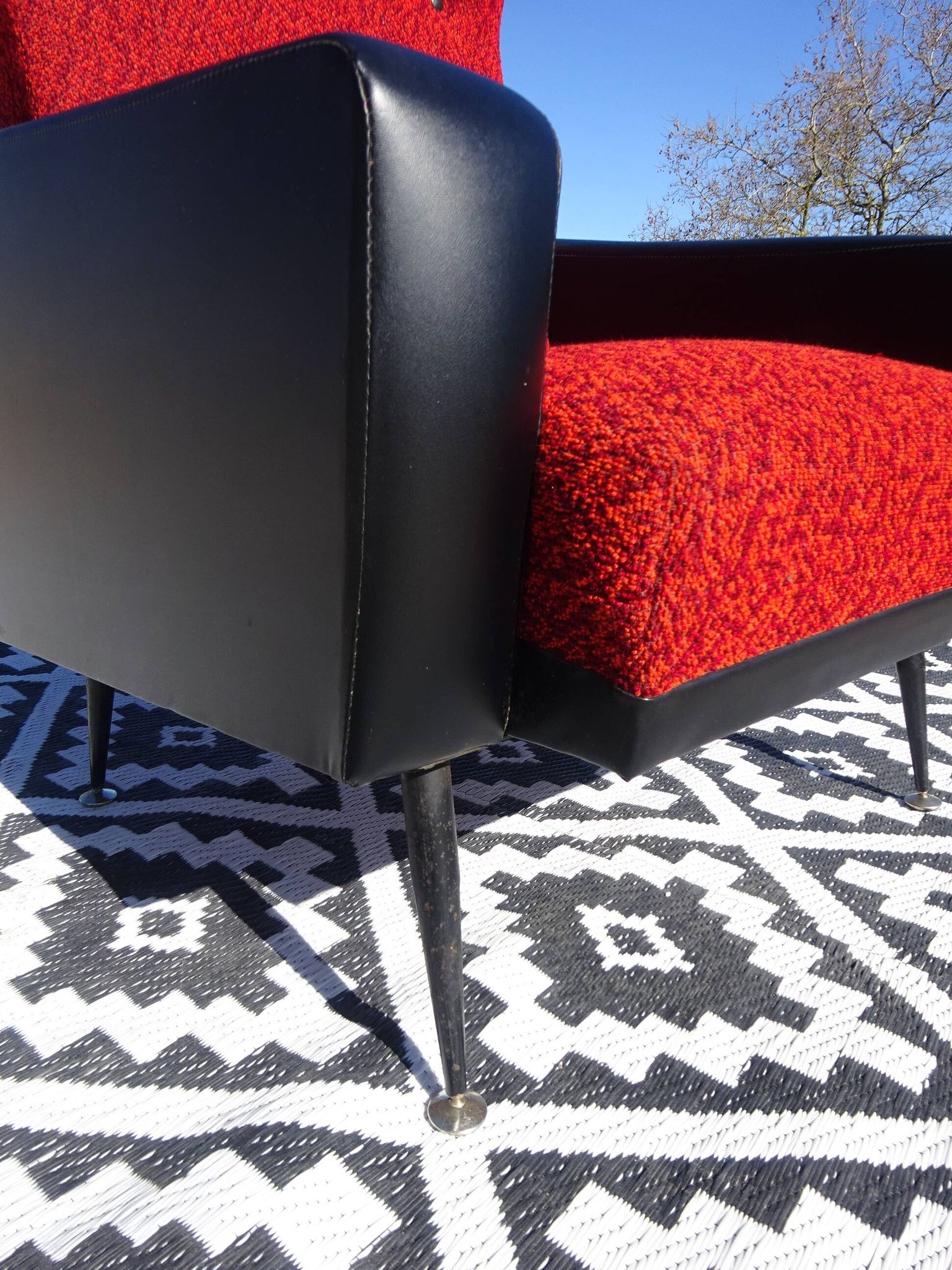 Pair of vintage armchairs in black faux leather and red fabric.