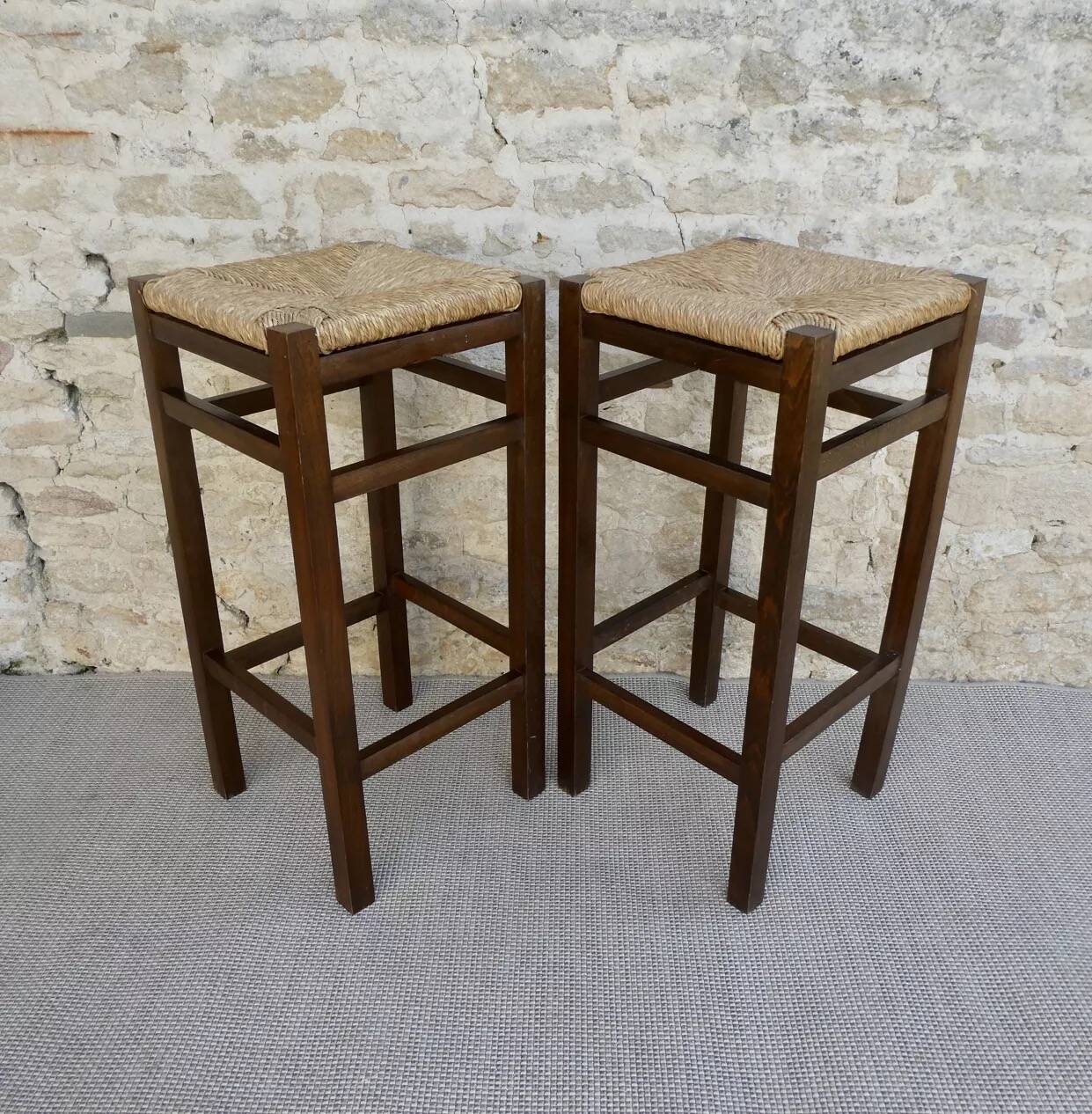 pair of bar stools, made of wood with a straw seat
