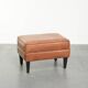 Handy sheepskin ottoman with warm colours finished with black piping