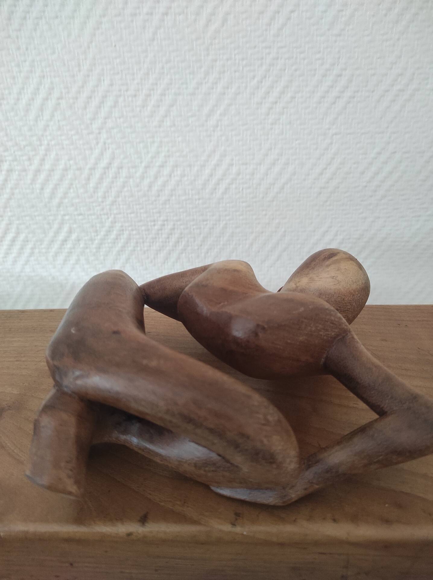 Wooden sculpted statuette of a woman in a pensive pose.