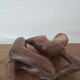 Wooden sculpted statuette of a woman in a pensive pose.