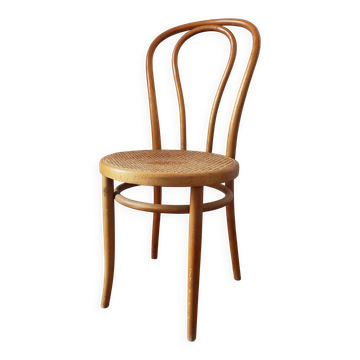 Vintage bistro chair in light wood with a curved design and caning.