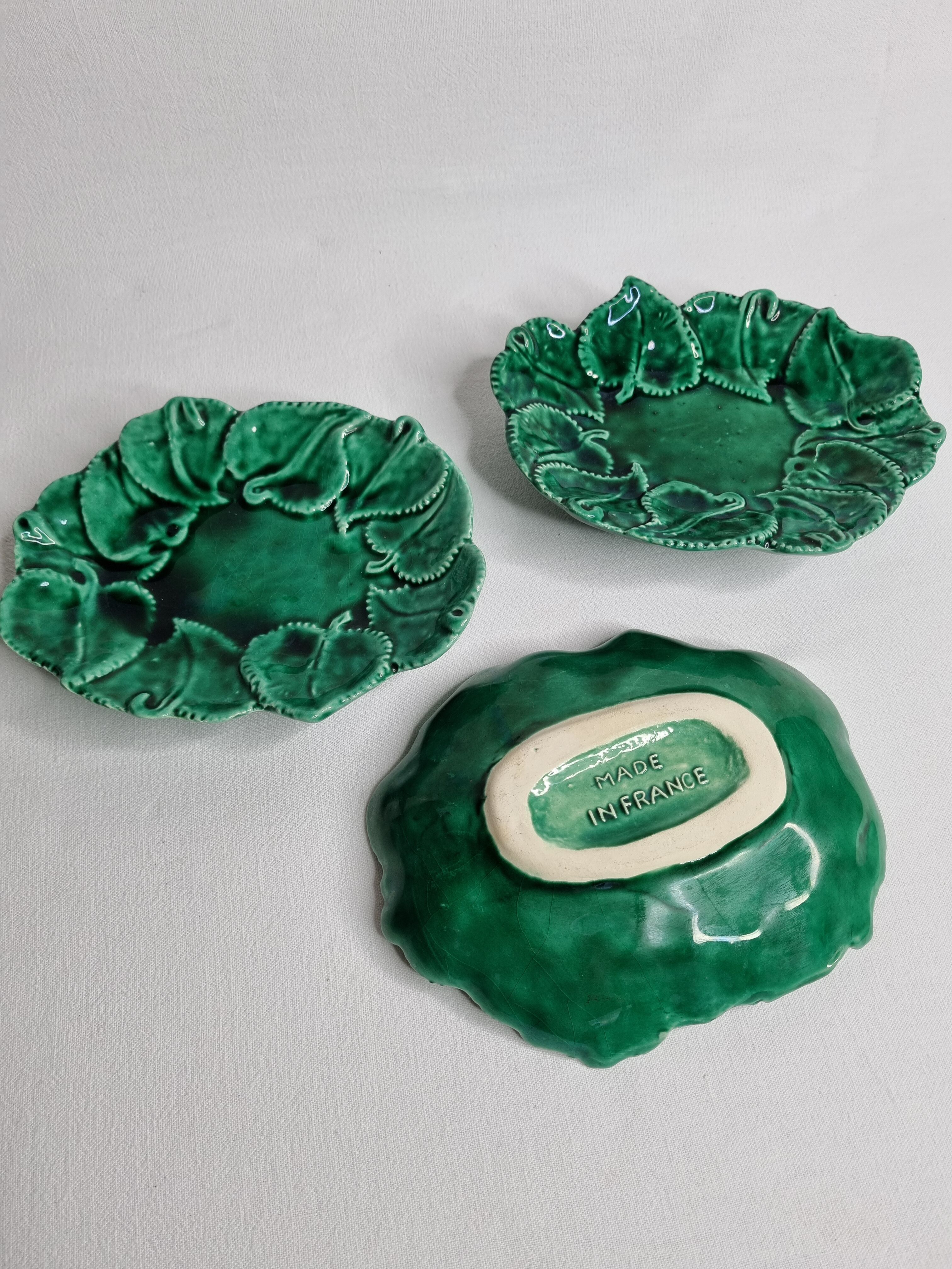 Set of three enamelled, emerald green, leaf-decorated faent cups